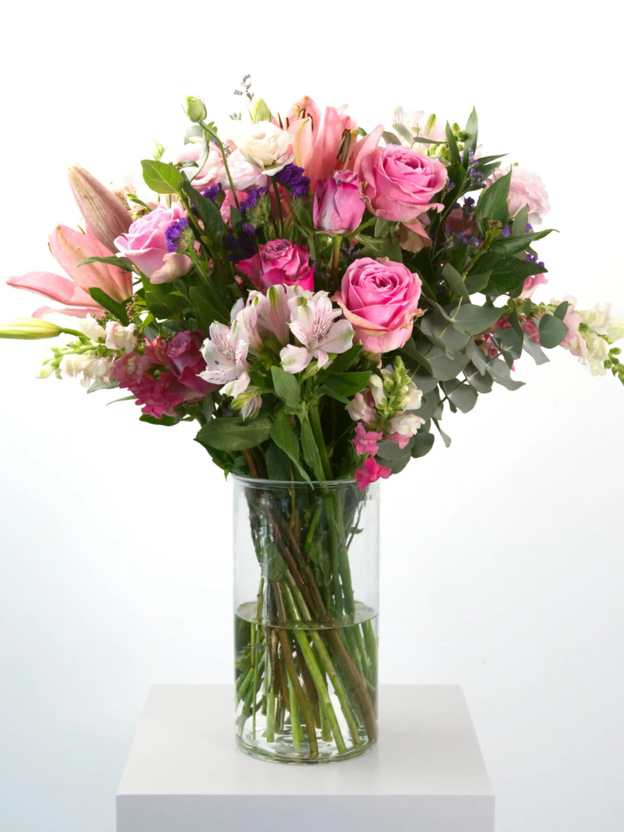 Deep, long-term passion captured in a single arrangement with pink and lilac roses, seasonal flowers and greenery. Presented in a glass vase or kraft paper tied with twine.