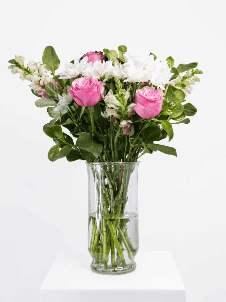 Pink, fuchsia, and white bouquet with lush greenery in a glass vase, offering a fresh and playful floral arrangement.