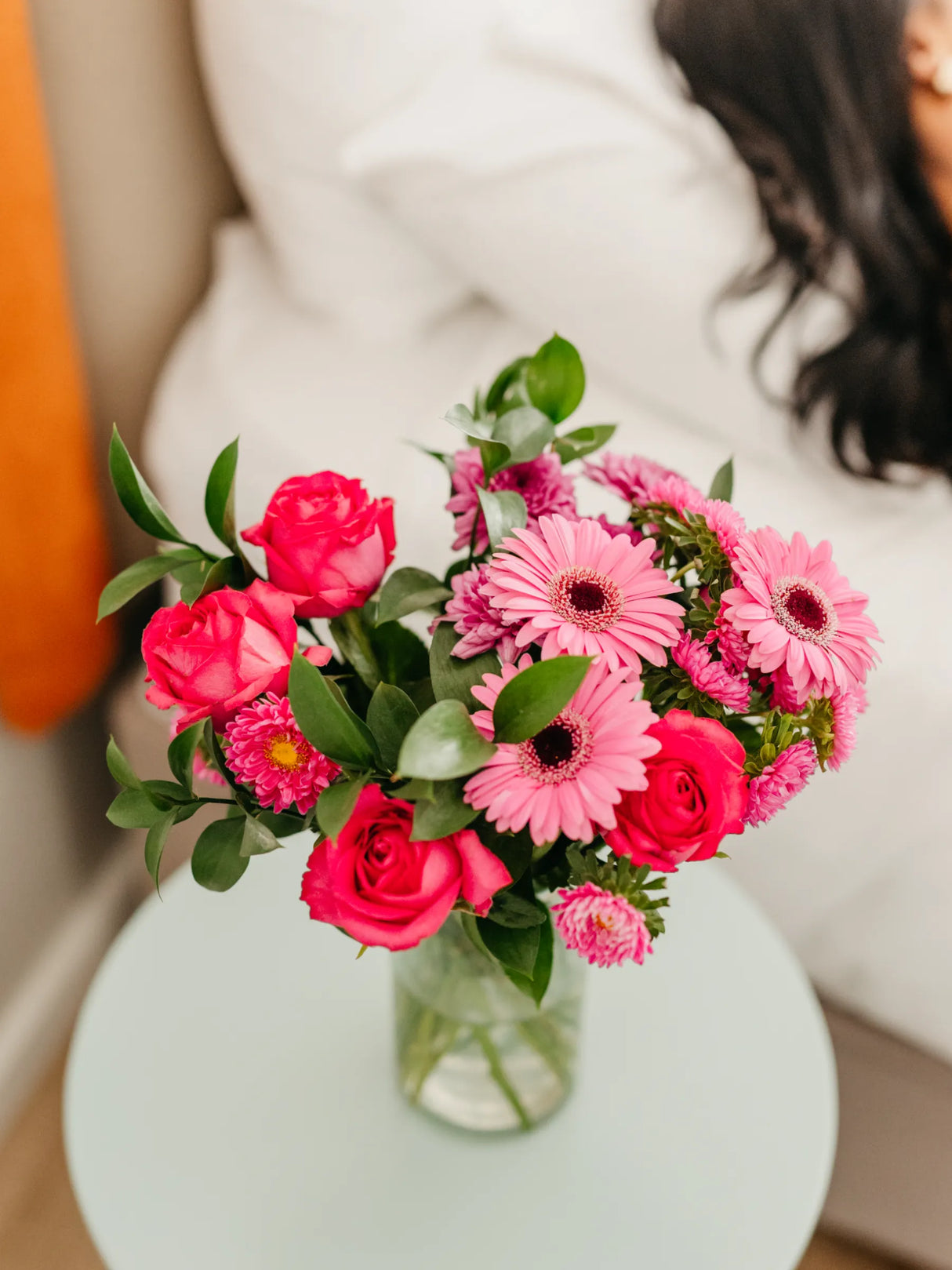 Bouquet of pink flowers in a clear vase on a light surface with a blurred background