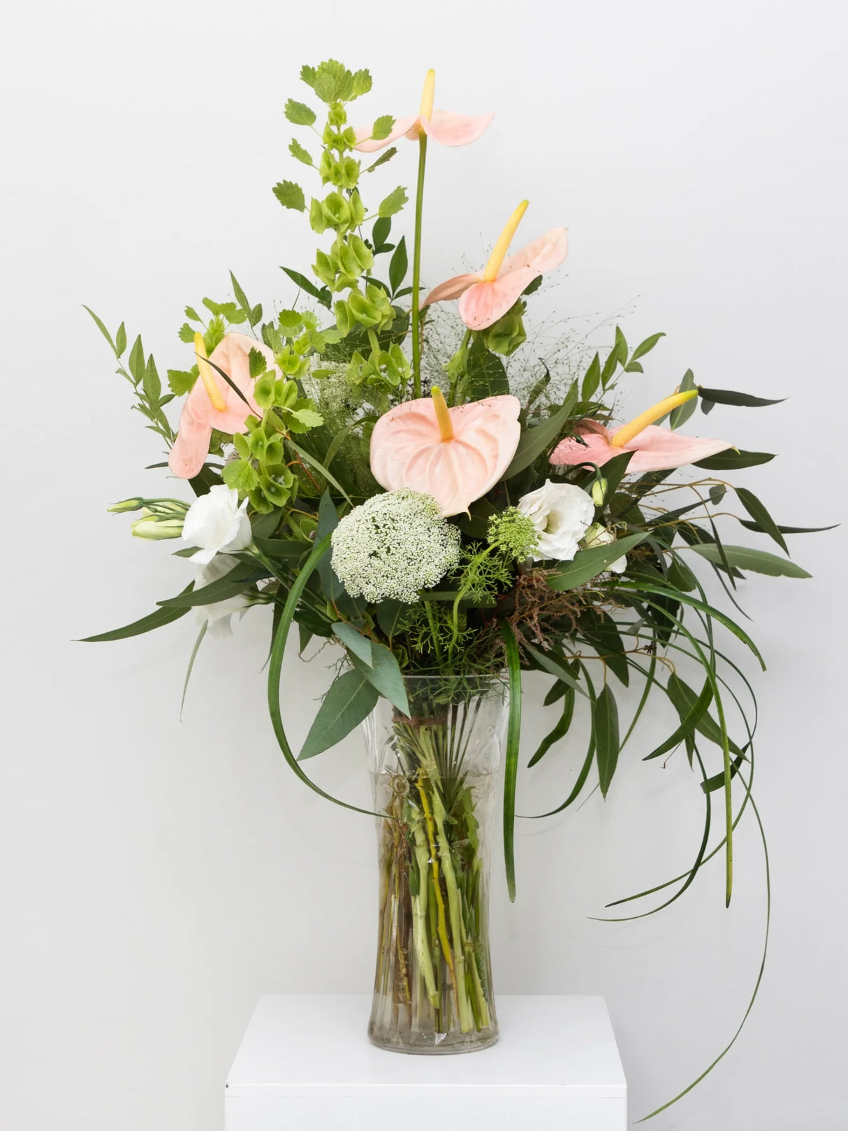 Bouquet of flowers in a clear vase on a white surface with a light gray background