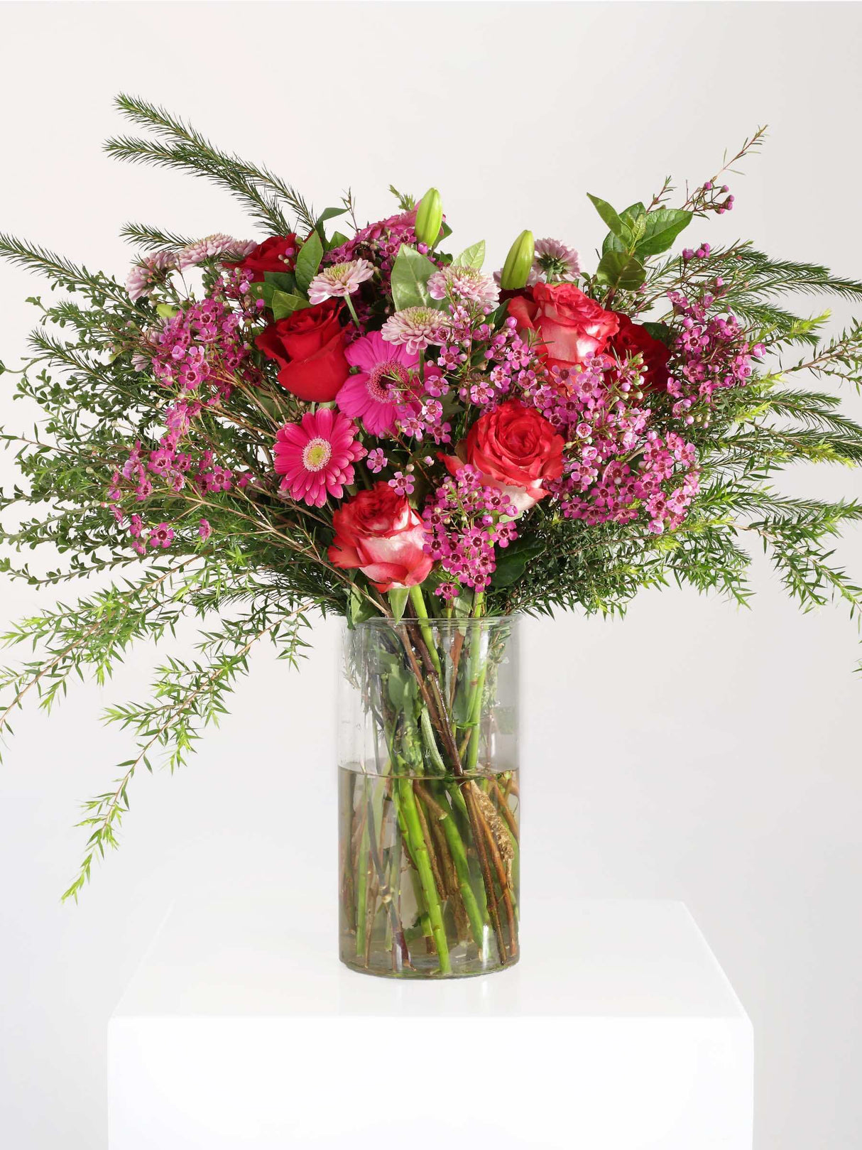Vibrant pink flower bouquet with roses, penny gum, and greenery arranged elegantly in a vase, ideal for any occasion.