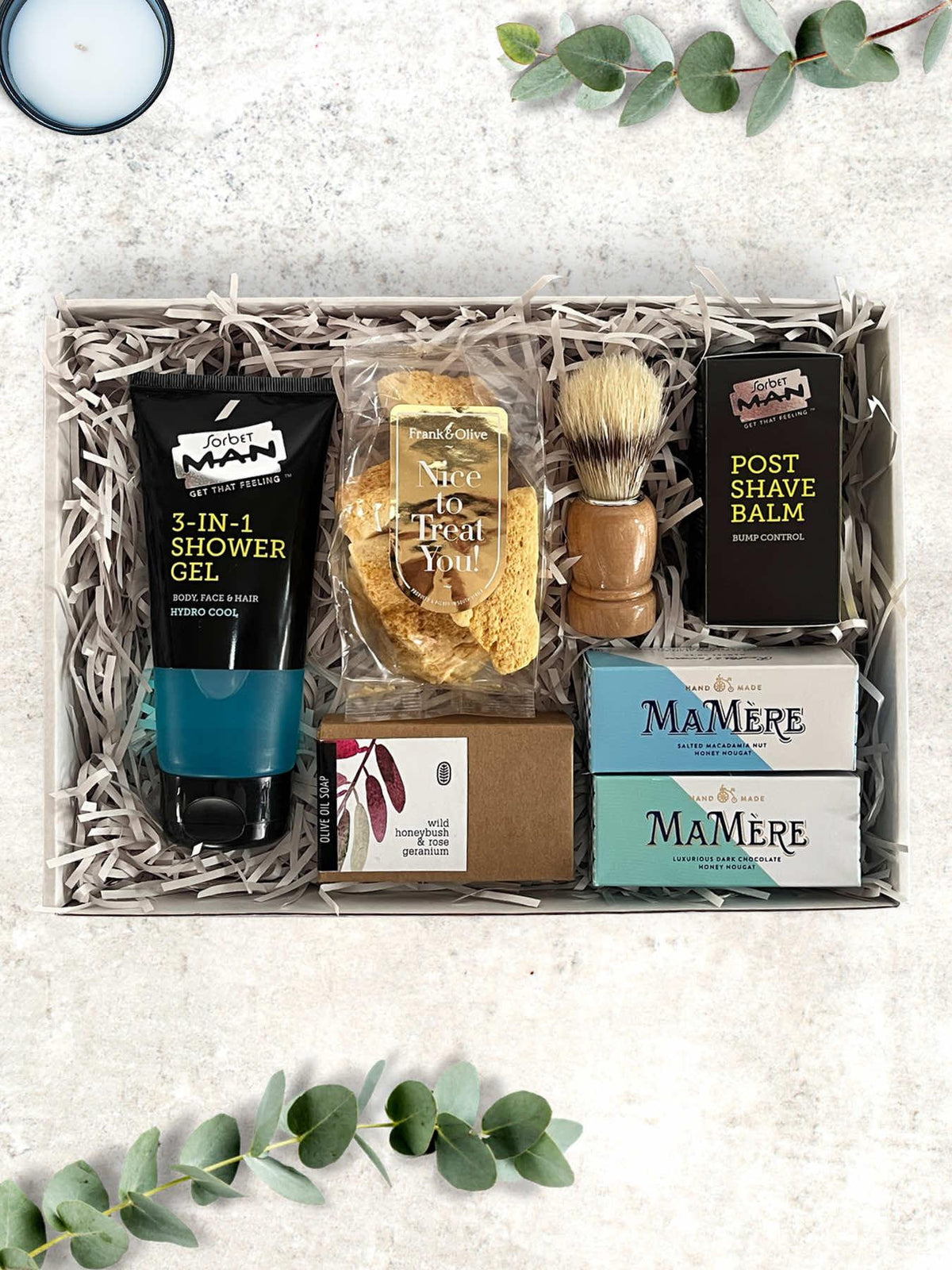 A luxury gift box for men containing olive oil soap, a shaving brush, post shave balm, shower gel, chocolate, and honey comb.