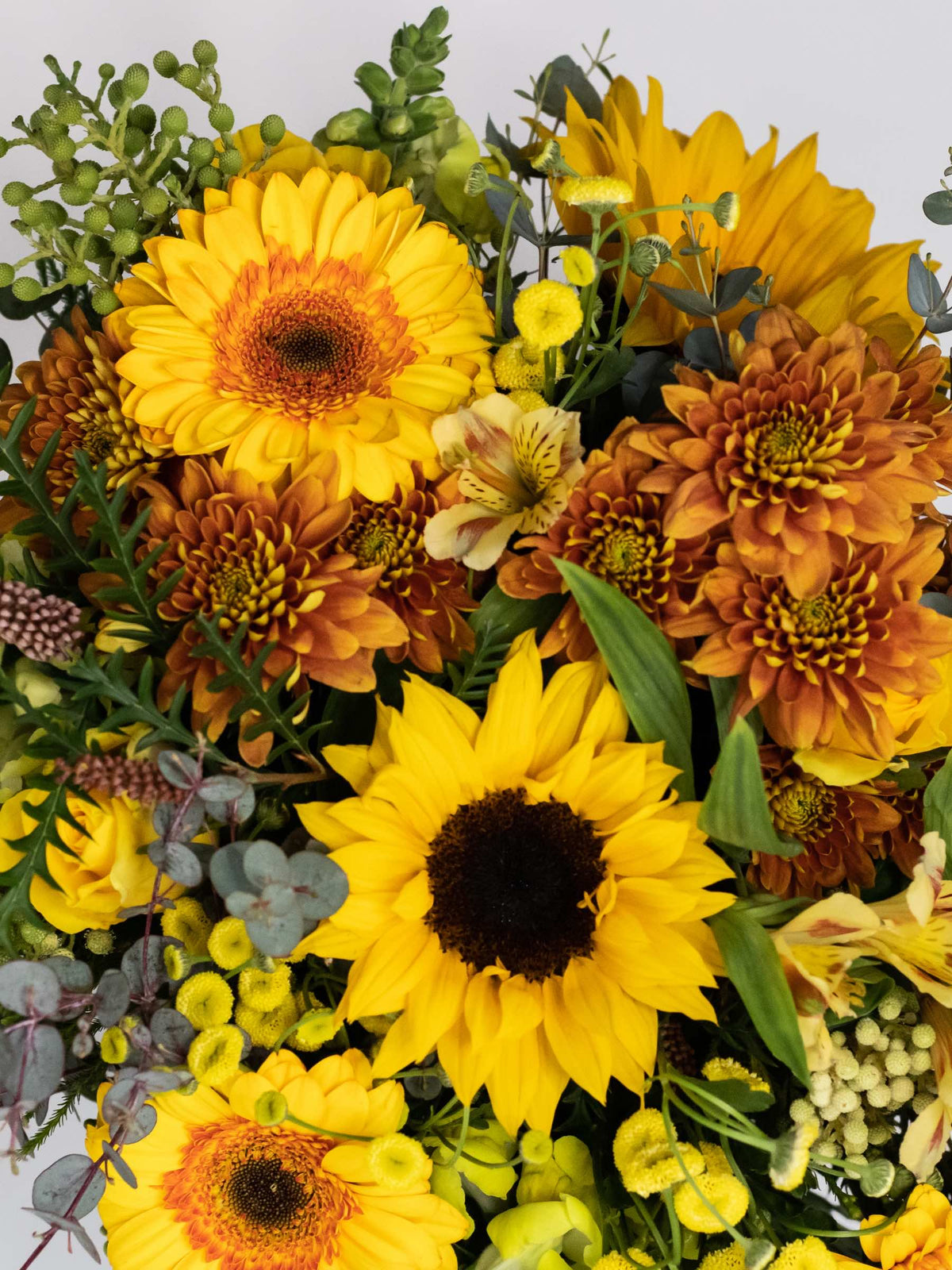 Close-up of Bloomable's Happy Bouquet featuring bright yellow sunflowers, golden-orange chrysanthemums, yellow gerbera daisies, delicate alstroemeria, and eucalyptus accents. A cheerful arrangement of sunshine-coloured flowers available with same-day delivery across South Africa.