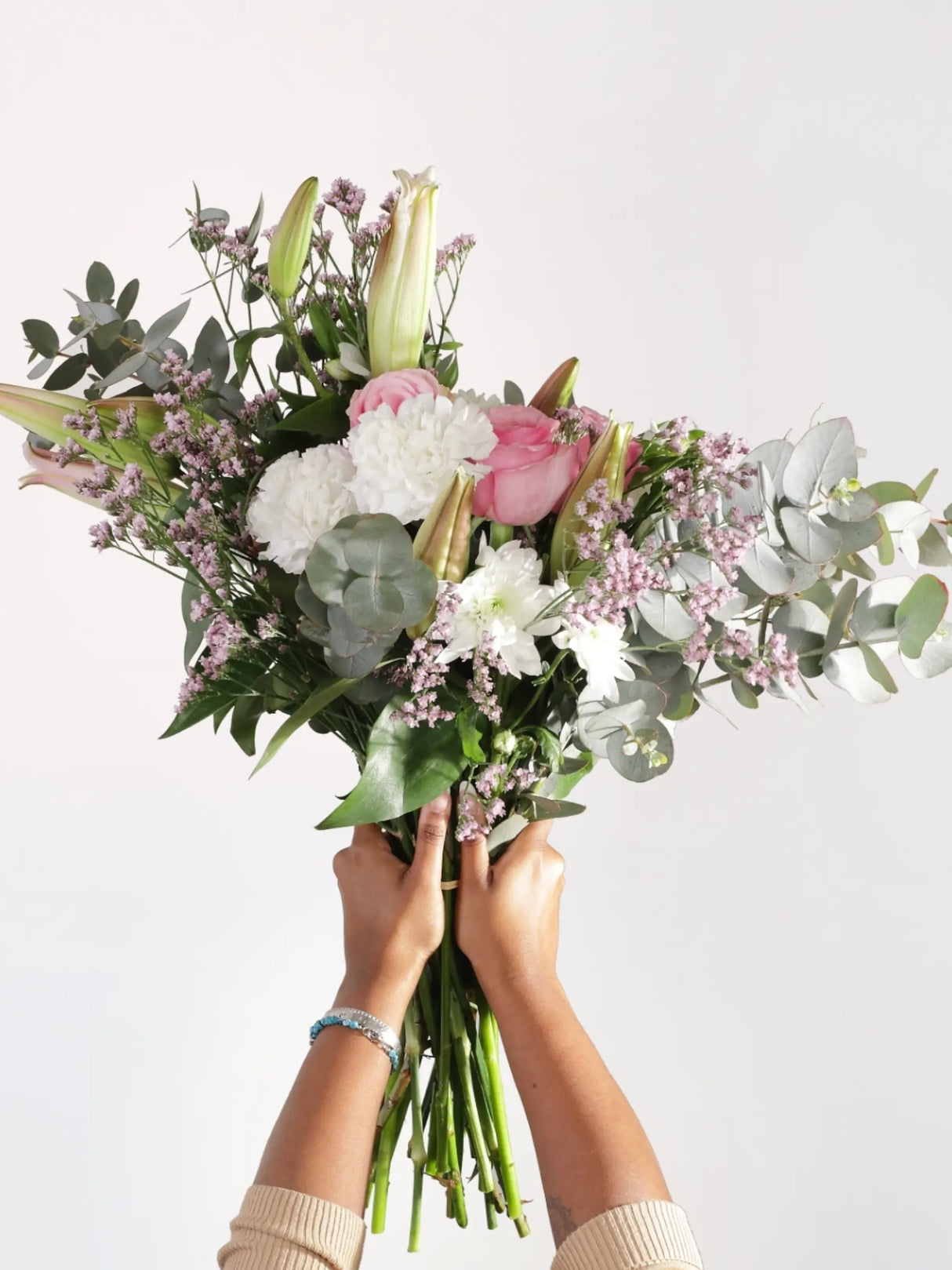 Hand-held pink and white bouquet featuring pink roses, white carnations, white chrysanthemums, pink waxflower and eucalyptus - elegant romantic flower gift held to show scale