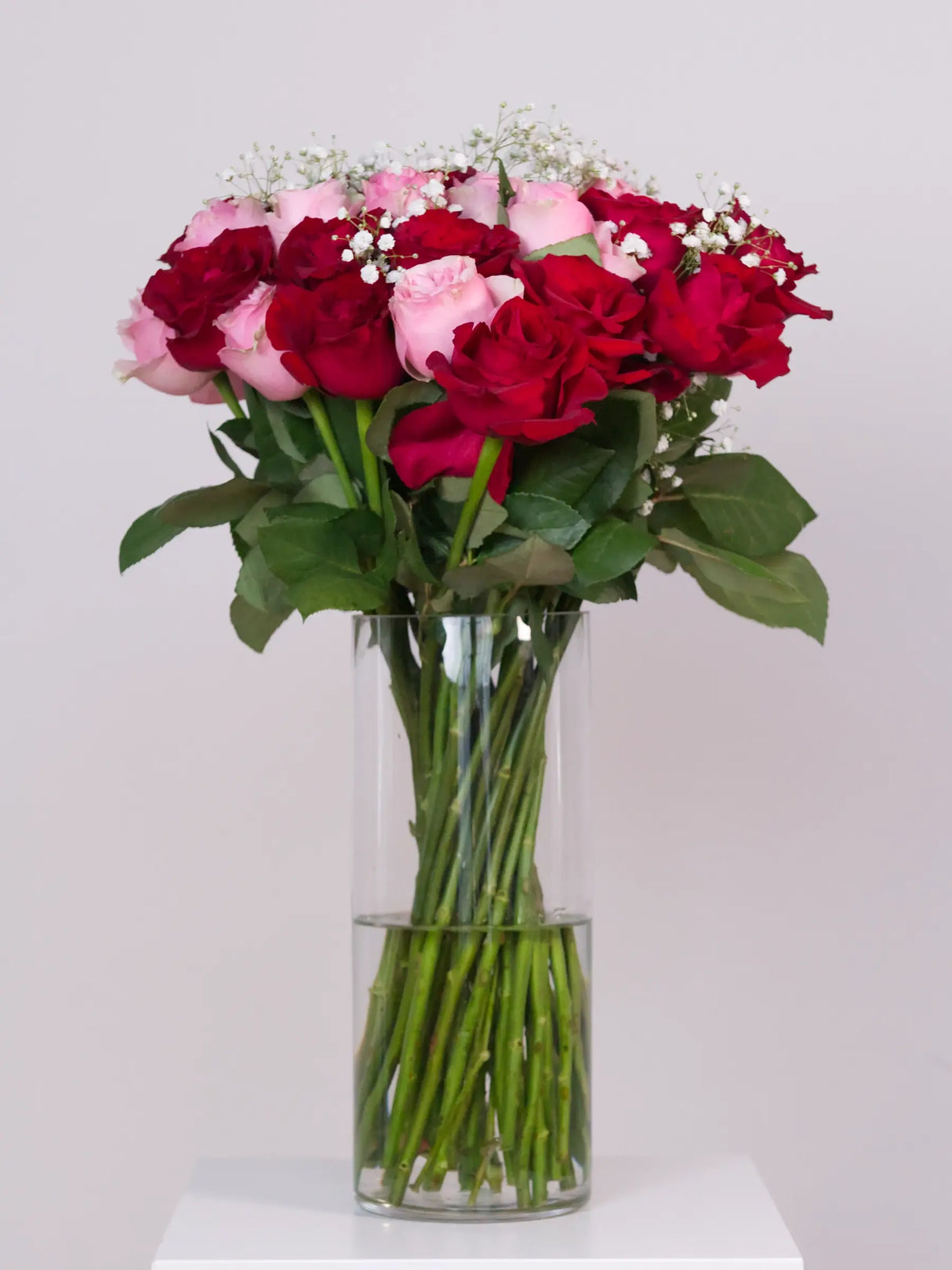 Bouquet of red and pink roses in a clear vase on a white background