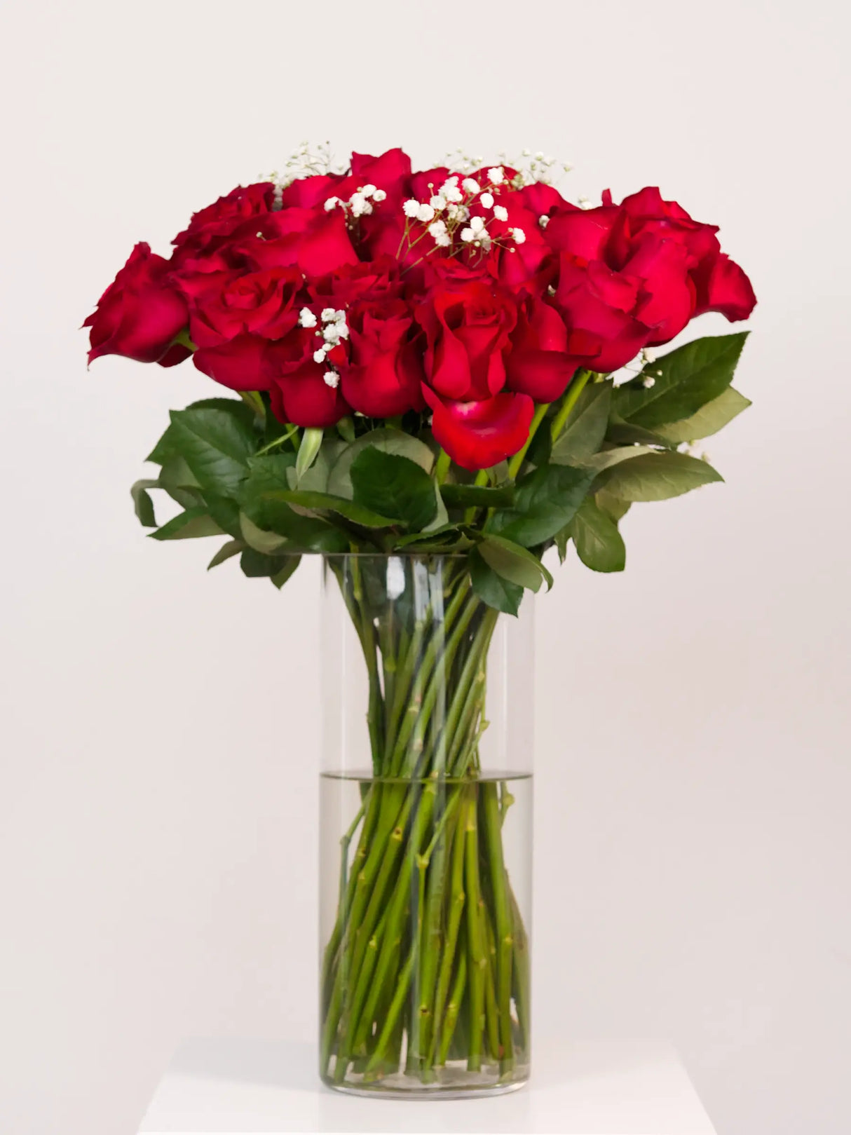 Bouquet of red roses in a clear vase on a white background