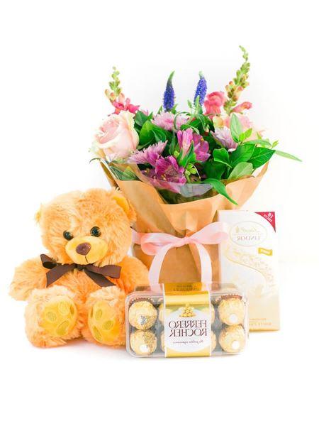 Newborn girl gift set with pink floral bouquet, teddy bear, luxury Lindt chocolate slab, and Ferrero Rocher chocolates.