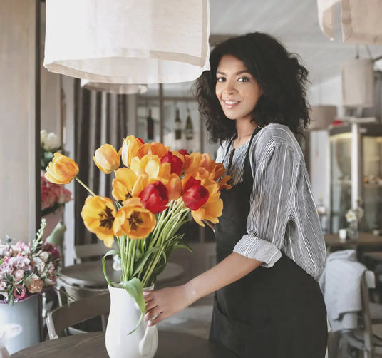 Woman holding a bouquet of yellow and red tulips in a restaurant setting