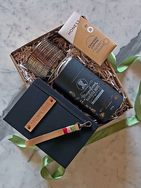 Gift box with coffee, chocolate, candle, notebook, and keychain from the ‘Brewed with Love’ collection, perfect for heartfelt moments.