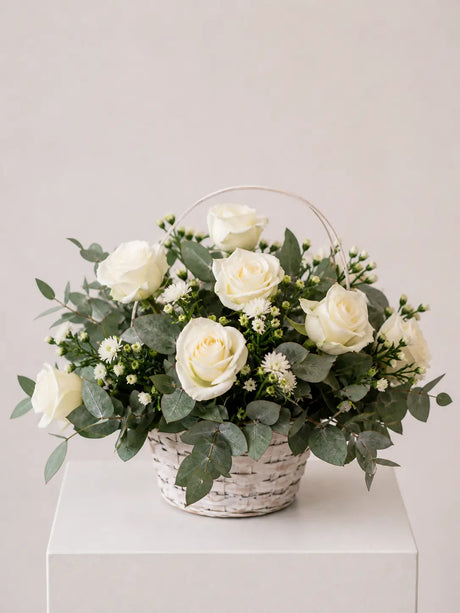 White rose and eucalyptus flower basket with wax flower in whitewashed wicker basket