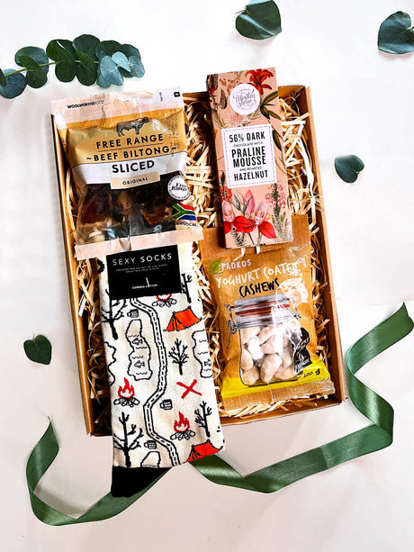 Snack and socks gift box with biltong, chocolate, coated nuts, and stylish socks, wrapped in a kraft box with ribbon and themed sticker.