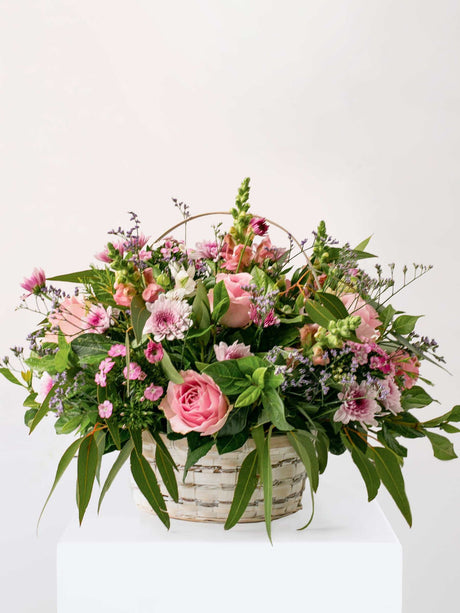 Country Basket with pastel seasonal flowers in a woven basket, featuring roses and greenery, perfect for a floral gift.