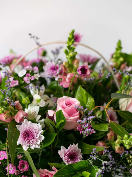Country basket with pastel seasonal flowers including roses and chrysanthemums, arranged beautifully as a perfect floral gift.