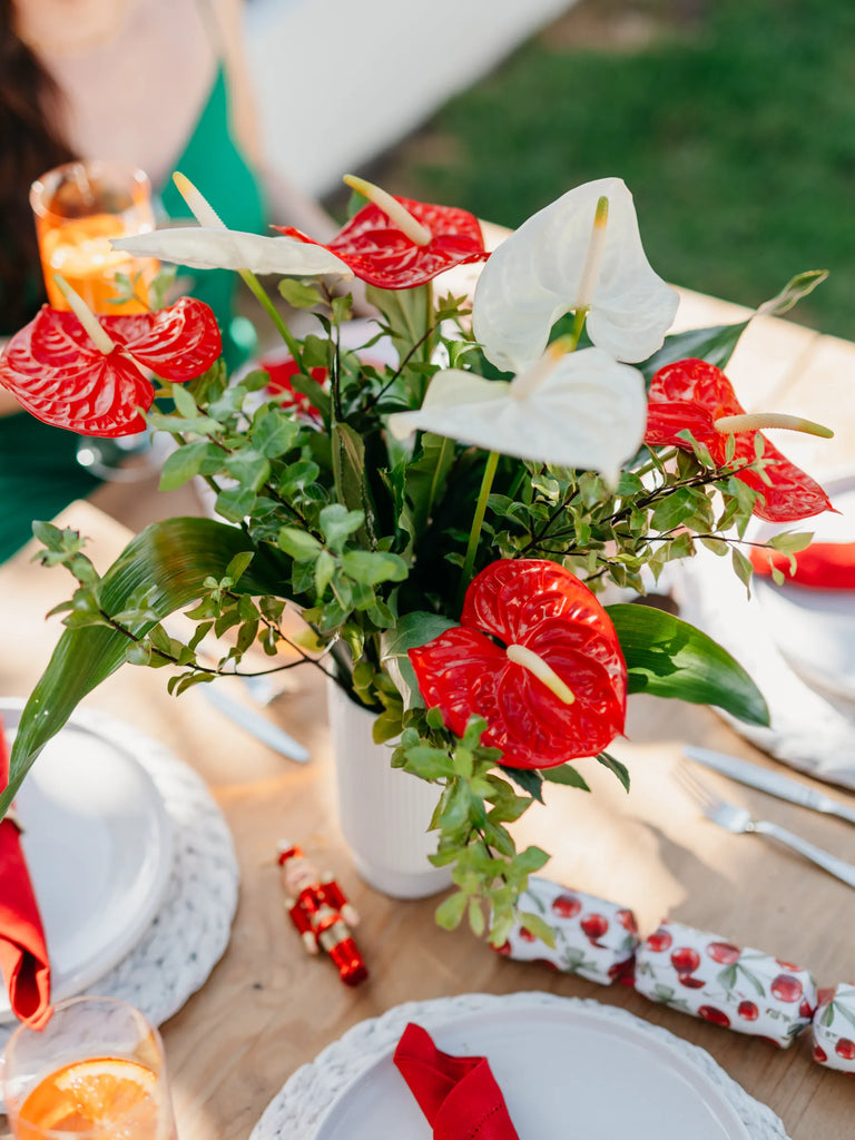 Red anthurium and white calla lily centrepiece on outdoor dining table - tropical wedding or party table decoration