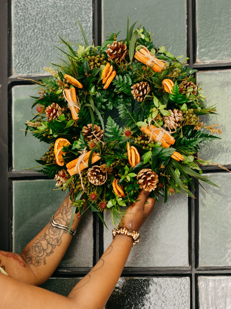 Natural Christmas wreath with dried orange slices, pine cones and evergreen foliage displayed on green door - rustic festive door decoration