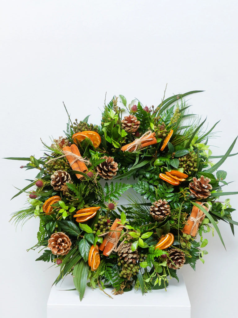 Natural Christmas wreath with dried orange slices, pine cones, mixed evergreen foliage and eucalyptus - rustic festive door decoration