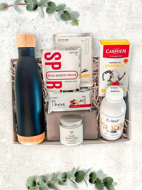 A gift box containing a black stainless steel water bottle, various health and wellness products, neatly arranged against a neutral background.