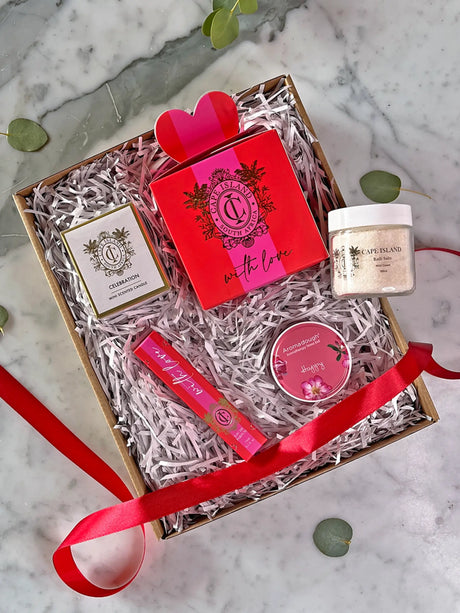 Gift set with a red box, jar, and other items on a marble surface