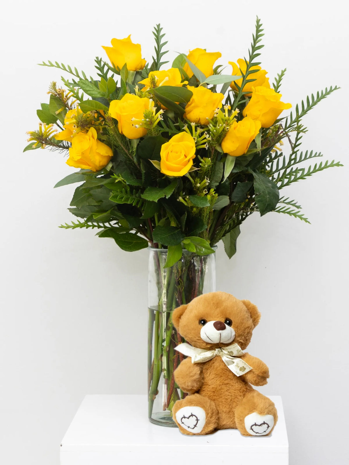 Bouquet of yellow roses in a vase with a teddy bear on a white background