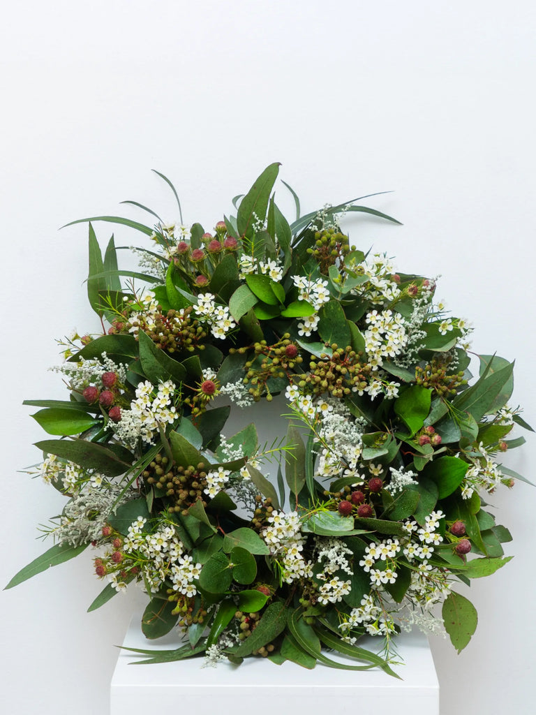 Rustic green Christmas wreath featuring white blooms, mixed eucalyptus foliage, burgundy berries, natural pine cones and greenery - organic festive door wreath
