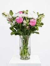 Pink, fuchsia, and white bouquet with lush greenery in a glass vase, offering a fresh and playful floral arrangement.