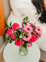 Bouquet of pink flowers in a clear vase on a light surface with a blurred background