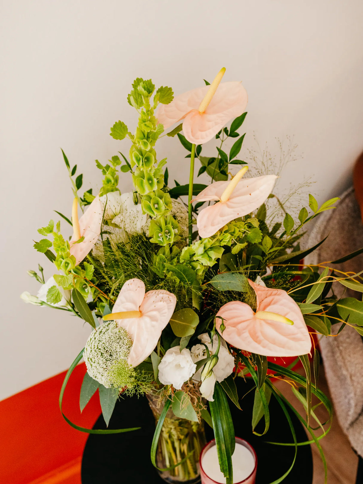 Bouquet of flowers with pink Anthuriums and green foliage on a neutral background
