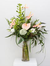 Bouquet of flowers in a clear vase on a white surface with a light gray background