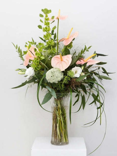 Bouquet of flowers in a clear vase on a white surface with a light gray background