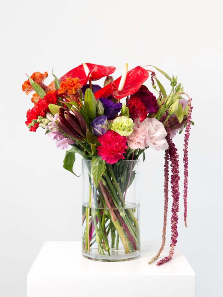 Just As You Are Bouquet featuring vibrant lilies, carnations, and cockscomb in a clear vase, celebrating romantic charm.