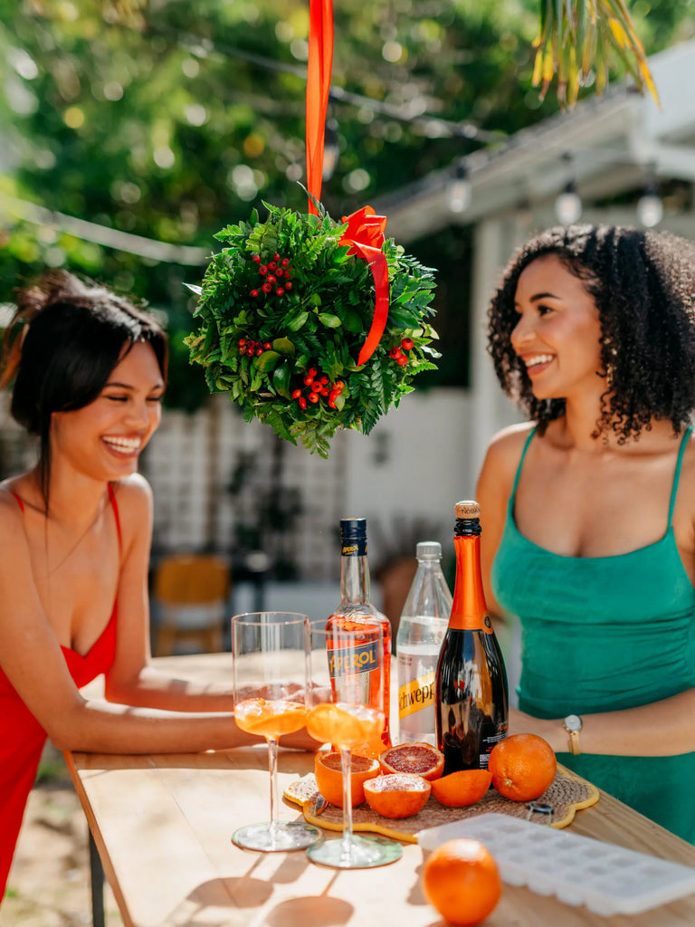 Fresh Christmas kissing ball with red berries and ribbon hanging at outdoor party - festive entertaining decoration with friends