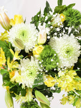 Fresh yellow and white flower bouquet close-up featuring yellow roses, white chrysanthemums, yellow alstroemeria, green dianthus and baby's breath - vibrant mixed arrangement detail