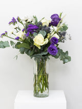 Bouquet of flowers in a clear vase on a white surface with a white background