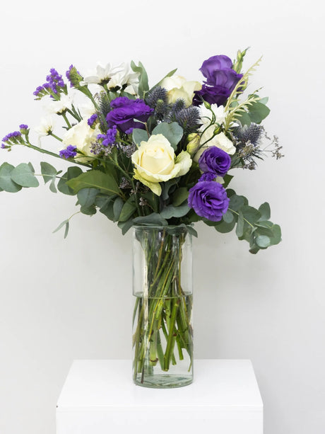 Bouquet of flowers in a clear vase on a white surface with a white background