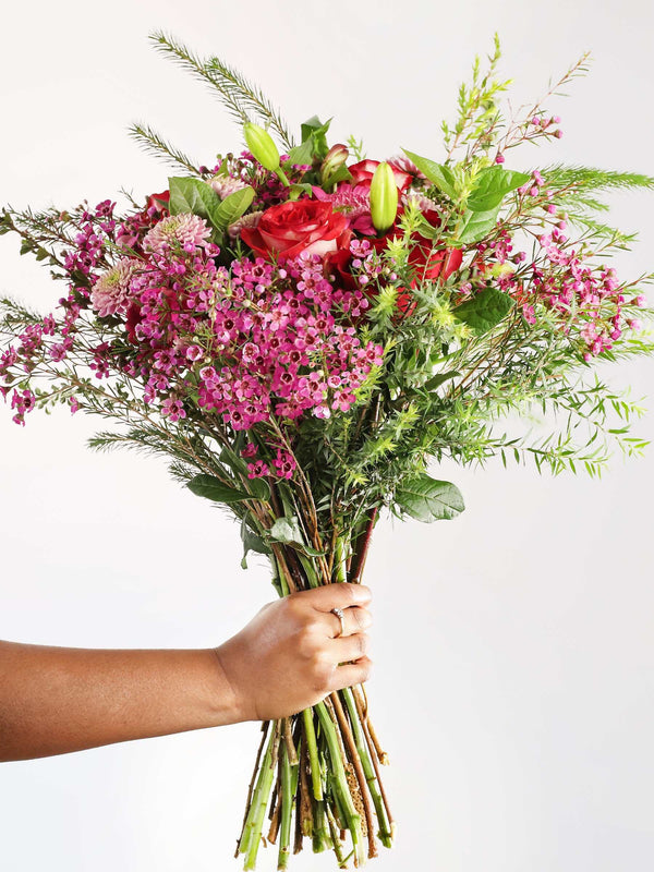 Bouquet of pink roses and penny gum with lush greenery, hand-held, showcasing a vibrant mix of blush hues perfect for any occasion.