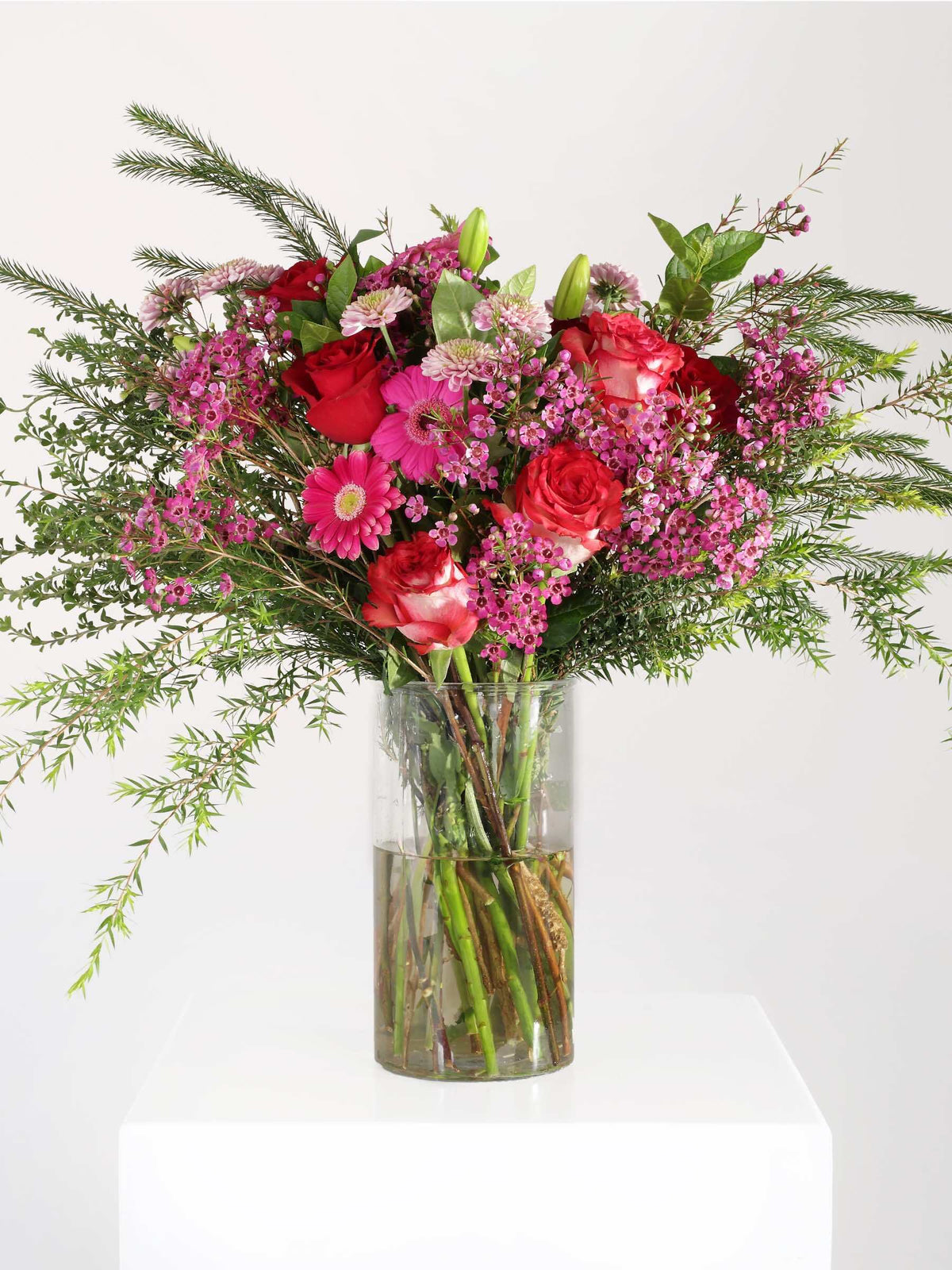 Vibrant pink flower bouquet with roses, penny gum, and greenery arranged elegantly in a vase, ideal for any occasion.
