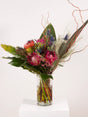 Proteas and pincushions with seasonal fynbos in a glass cylinder vase, the ideal gift for Boss's Day or a corporate birthday.