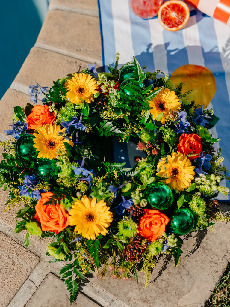 Colorful flower arrangement with greenery on a stone surface near a pool.