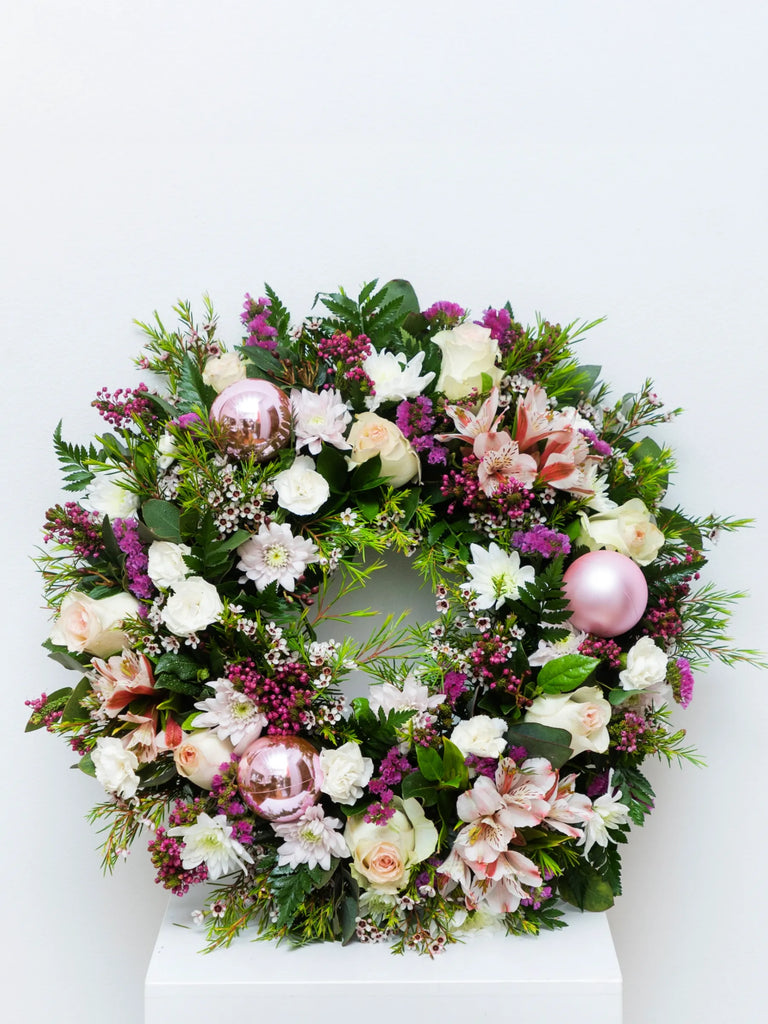 Pink and white Christmas wreath with roses, carnations, baby's breath, evergreen foliage, rose gold baubles and burgundy berries - luxury festive door decoration