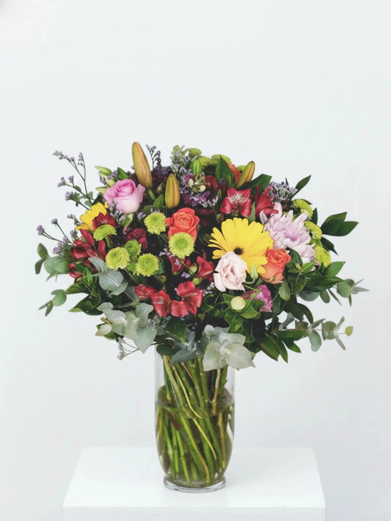 Bouquet of colorful flowers in a clear vase on a white background