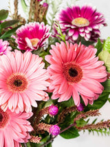 Mixed gerbera bouquet with light and dark pink daisies and greenery, symbolizing love, gratitude, and romance.
