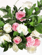 Pink and white pastel roses with lush green leaves, elegantly arranged to enhance any space with beauty and warmth.
