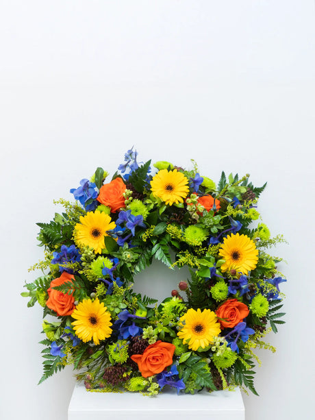 Multicoloured round wreath with mixed seasonal flowers for a funeral or memorial.
