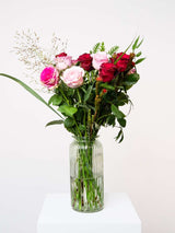 Bouquet of pink and red roses with greenery in a clear vase, perfect for Valentine's Day, symbolizing love and romance.
