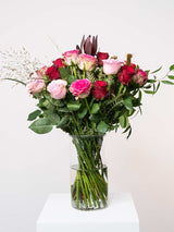 Valentine's Day bouquet with pink and red roses, contrasting greenery in glass vase, ideal romantic gift for love and passion.