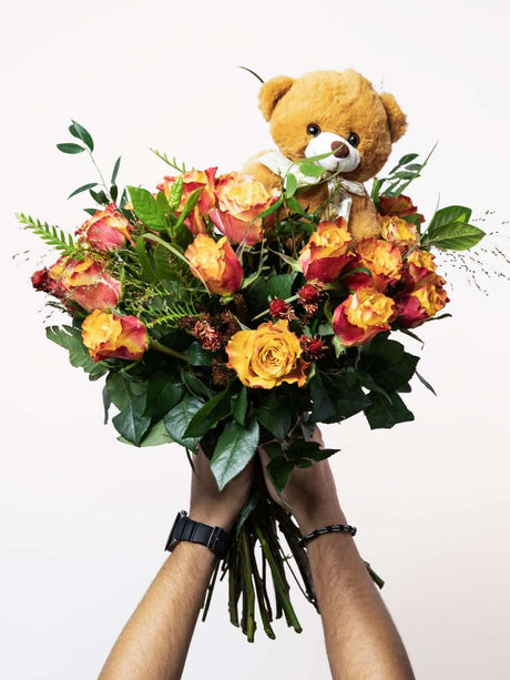 Vibrant bouquet of orange roses with a small teddy bear, perfect for Valentine's Day gift, expressing joy and affection.