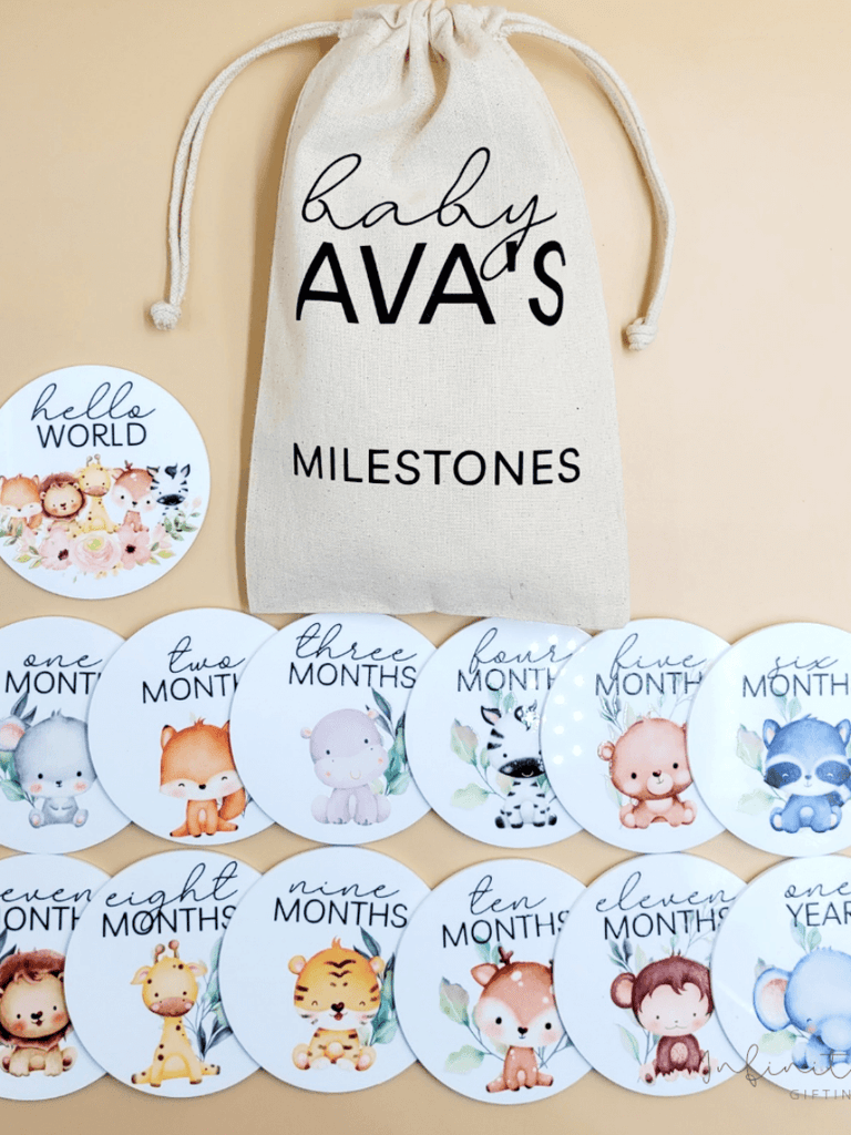 Personalised baby milestone disc set featuring 12 monthly discs with adorable baby animal illustrations, plus a 'hello world' disc, with a soft cotton drawstring bag for storage.