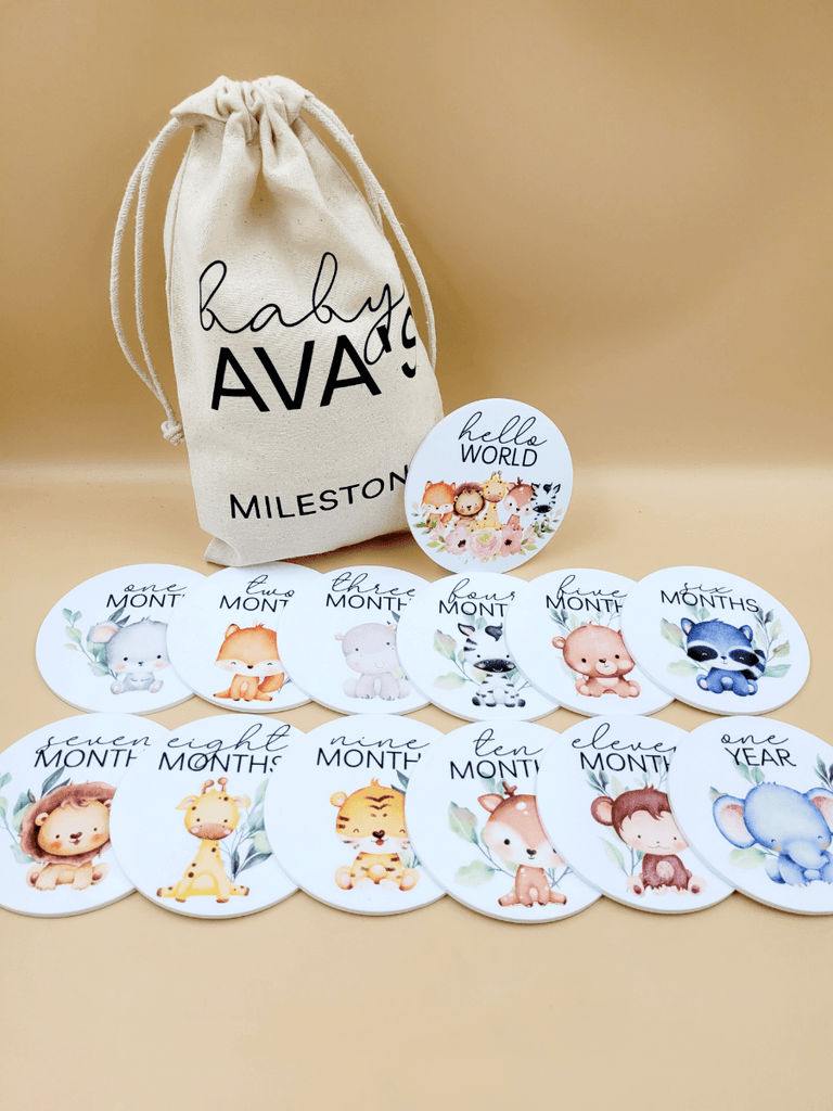 Personalised baby milestone disc set featuring 12 monthly discs with adorable baby animal illustrations, plus a 'hello world' disc, with a soft cotton drawstring bag for storage.