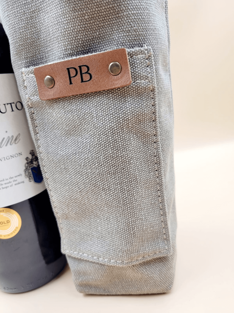 Personalised canvas leather wine carrier with initials PB, featuring a bottle and elegant craftsmanship.
