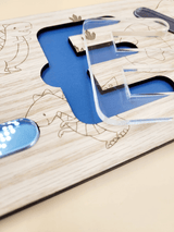 Close-up of a personalised engraved name puzzle for kids with dinosaur theme, featuring clear acrylic letters and oak veneer base.